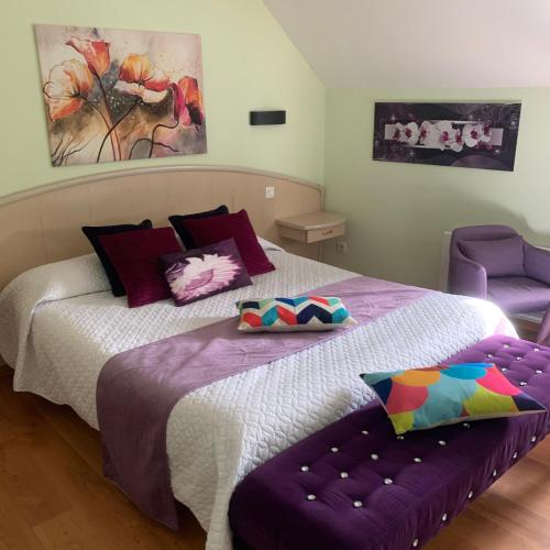 a bedroom with two beds and a purple chair at Auberge Du Cheval Blanc in Beaumont-Pied-de-Boeuf