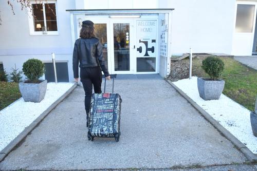 a woman walking down a sidewalk pulling a suitcase at Motel55 - nettes Hotel mit Self Check-In in Villach, Warmbad in Villach