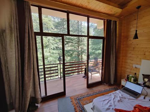 a room with a bed and a large glass door at WildWoodHome Jibhi in Jibhi