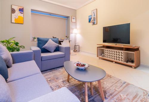 a living room with a couch and a tv at Trinity Holiday Homes - Sheikh Zayed Road Near to Financial Center Metro Station in Dubai