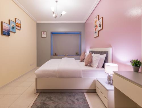 a bedroom with a white bed and a pink wall at Trinity Holiday Homes - Sheikh Zayed Road Near to Financial Center Metro Station in Dubai