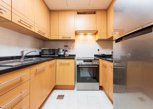a kitchen with wooden cabinets and stainless steel appliances at Trinity Holiday Homes - Sheikh Zayed Road Near to Financial Center Metro Station in Dubai