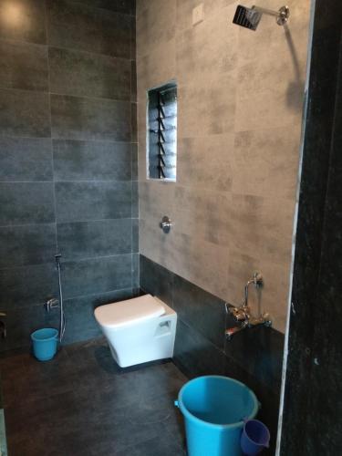 uma casa de banho com um WC, uma janela e um balde em Aamantran Residency em Dapoli