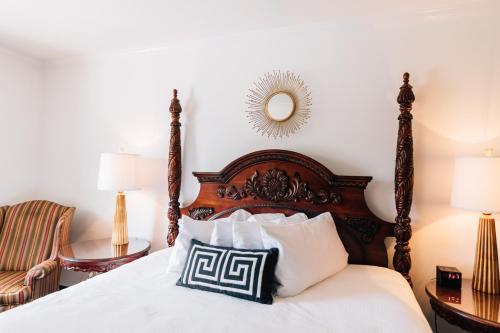 a bedroom with a bed and a chair and a mirror at Church Street Inn in Natchitoches