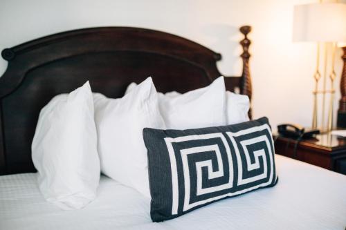 a bed with white pillows and a black and white pillow at Church Street Inn in Natchitoches