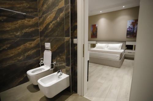 a bathroom with a toilet and a sink and a bed at Admiral Hotel in Elbasan