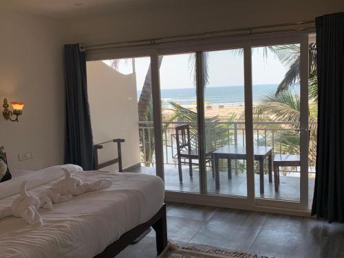 a bedroom with a bed and a view of the ocean at Chique Shanti Resort in Mandrem