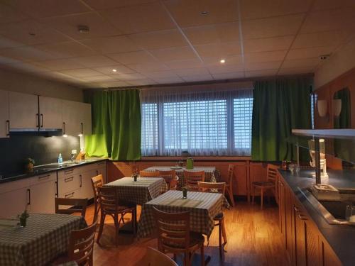 un restaurante con mesas, sillas y cortinas verdes en Hotel Vi Vintage S-Weilimdorf, en Stuttgart-Weilimdorf