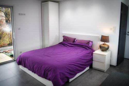 Dormitorio blanco con cama morada y ventana en L'à Côté, en Colmar