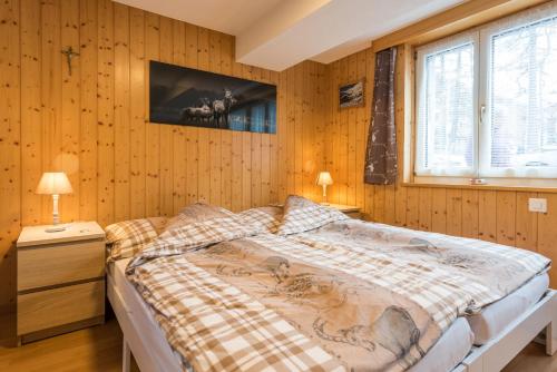 ein Schlafzimmer mit Holzwänden und einem großen Bett in der Unterkunft Haus Alpenblick in Saas-Grund