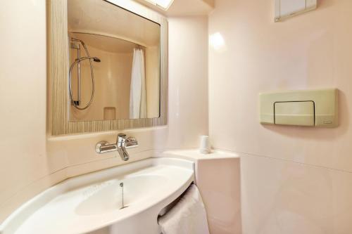 a white bathroom with a sink and a mirror at Premiere Classe Dijon Sud - Marsannay in Marsannay-la-Côte