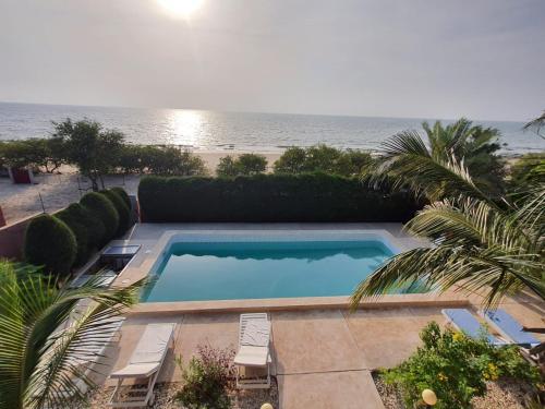 a swimming pool with a view of the beach at la villa sur la plage in Palmarin
