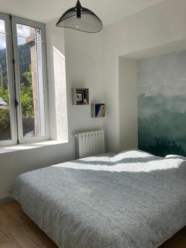 une chambre blanche avec un lit et une fenêtre dans l'établissement La Parisette, à La Bourboule