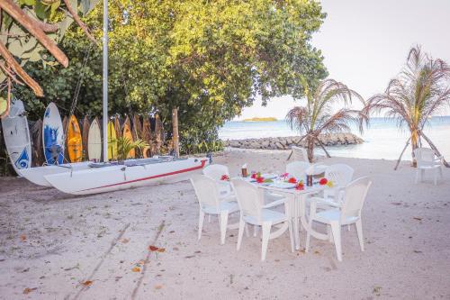 a table and chairs on a beach with a boat at Summer Vibes Beach Front in Rasdu