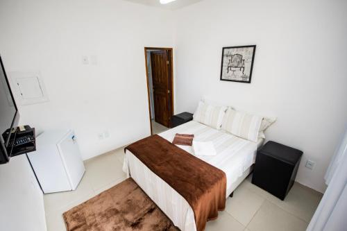 a small bedroom with a bed and a television at Pousada Quatro Estações Paraty in Sertão do Taquari