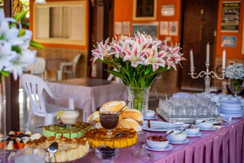 a purple table with food and a vase of flowers at Pousada Quatro Estações Paraty in Sertão do Taquari