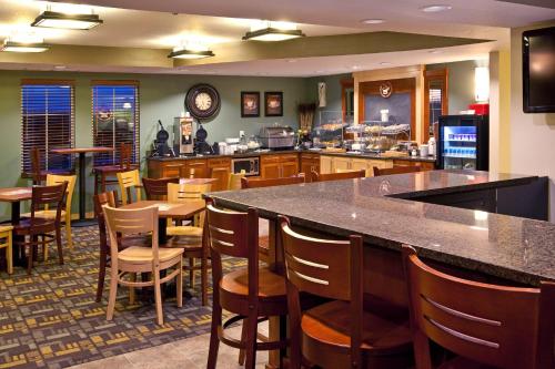 a restaurant with a bar and some tables and chairs at AmericInn by Wyndham Osage in Osage