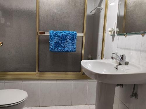 ein Bad mit einem Waschbecken und einer Dusche mit einem blauen Handtuch in der Unterkunft Residencial Pinar San Rafael (VuT) in San Rafael