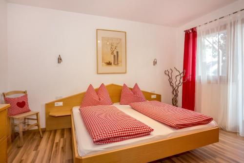 Schlafzimmer mit einem Bett mit roten und weißen Kissen in der Unterkunft Lampenhof in Bruneck