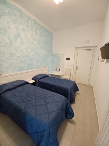 2 letti in una camera con trapunte blu di Hotel Costa a Bari