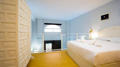 una camera da letto con un grande letto bianco e una finestra di RentalSevilla Sol y Pasión a Siviglia