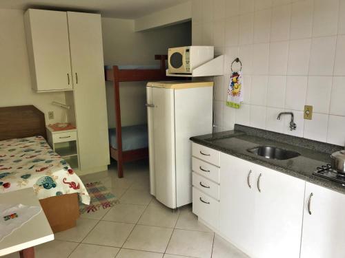 uma cozinha com um frigorífico branco e um lavatório em Residencial Caminho das Pedras - Praia da Solidão em Florianópolis