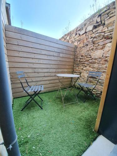 two chairs and a table in front of a wall at Appartements C'Home un charme in Lannion