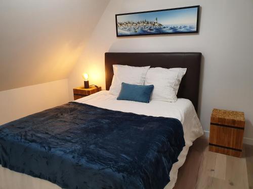 een slaapkamer met een groot bed met een blauw kussen bij Appartements C'Home un charme in Lannion