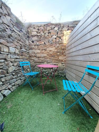 two chairs and a table next to a stone wall at Appartements C'Home un charme in Lannion