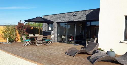 a wooden deck with chairs and an umbrella at Logement Privatif à 5min du lac de Rille in Savigné-sur-Lathan
