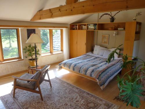 a bedroom with a bed and a chair and windows at B&B Pinorama in Sutton