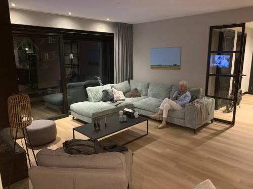 a woman sitting on a couch in a living room at New high end waterfront family villa in Stavoren