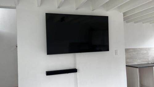 einen Flachbild-TV, der an einer weißen Wand hängt in der Unterkunft Luxury Suites at The Square Duplex Townhouse in Springfield