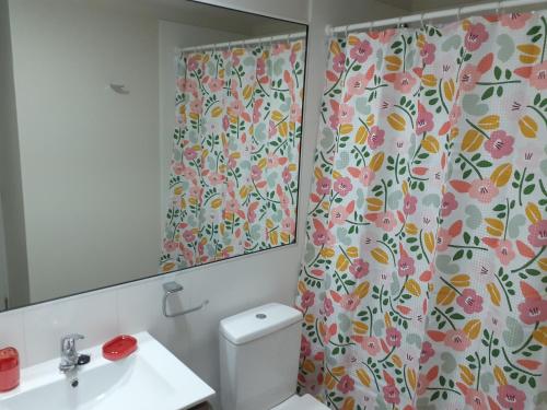 a bathroom with a shower curtain with a flower pattern at Departamento Pucón in Pucón