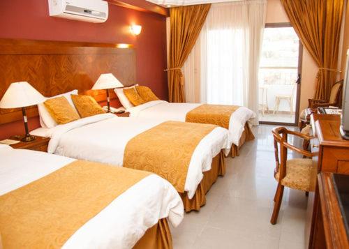 a hotel room with three beds and a window at Al Anbat Hotel & Restaurant in Wadi Musa