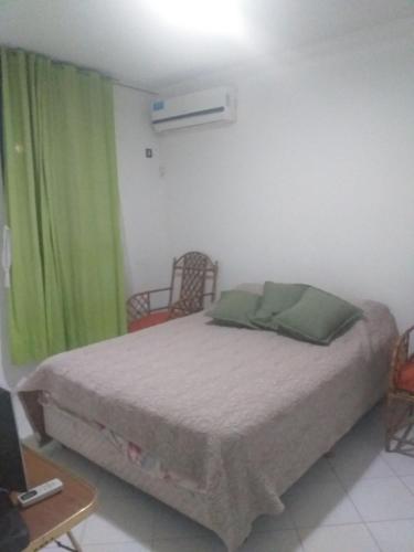 1 dormitorio con 1 cama con cortina verde en Serena en Villa Carlos Paz