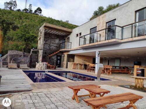 a house with a swimming pool and two wooden benches at Recanto Serra Monte in Alto Caparao