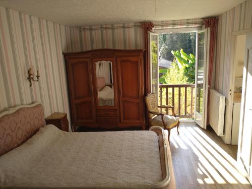 een slaapkamer met een bed, een kast en een balkon bij Gîte du Moulin de la Roque in Castels