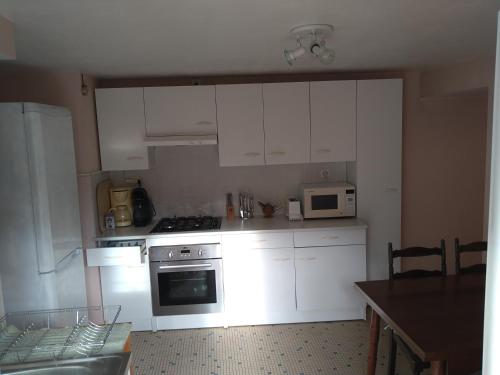 een keuken met witte kasten, een fornuis en een magnetron bij Gîte du Moulin de la Roque in Castels