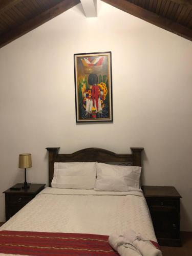 a bedroom with a bed with a picture on the wall at Hotel Mansion Del Rey in Antigua Guatemala