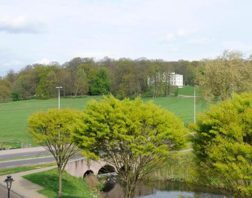 a bridge over a river with trees and a white building at Hotel Molendal in Arnhem