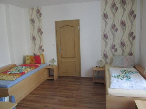 a small room with two beds and a door at Pension U Vlášků in Karlovy Vary