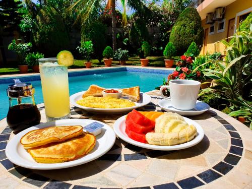 a table with plates of breakfast food and a drink at Hotel Los Pinos in Managua