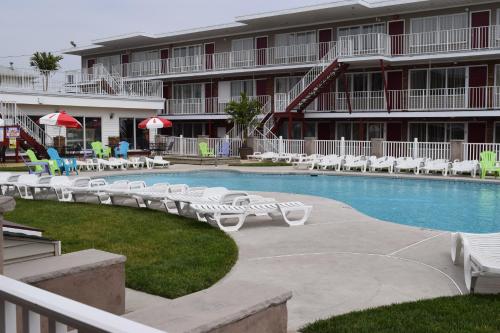 a resort with a swimming pool with lounge chairs and a hotel at Hershey Motel in Seaside Heights