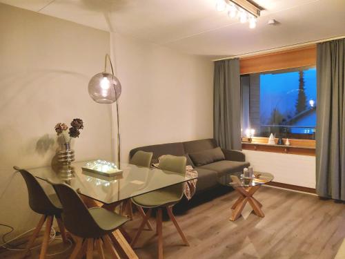 uma sala de estar com uma mesa de vidro e um sofá em LAAX Central Holiday Apartment with Pool & Sauna em Laax