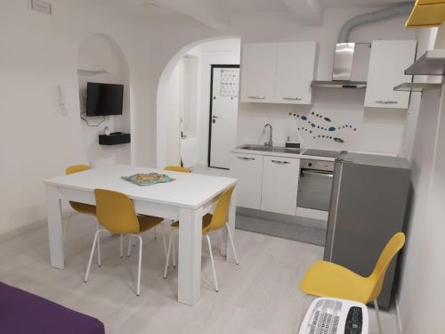 eine Küche mit einem weißen Tisch und gelben Stühlen in der Unterkunft HOLIDAY HOUSE FIERAVECCHIA in Salerno