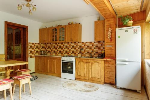 a kitchen with a white refrigerator and wooden cabinets at Хата Різьбяра - Закуток in Beloberëzka