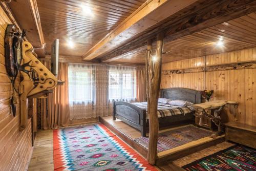 een slaapkamer met een bed in een houten kamer bij Хата Різьбяра - Закуток in Beloberëzka