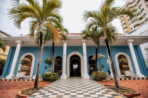 a blue building with palm trees in front of it at Casa Bustamante Hotel Boutique in Cartagena de Indias