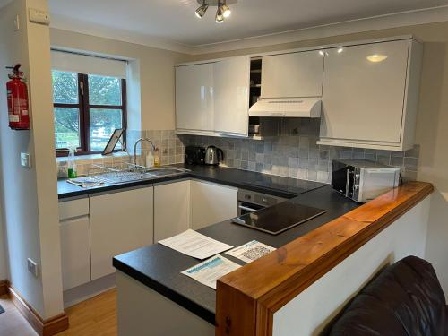 a kitchen with white cabinets and a black counter top at Rose Cottage in Camelford